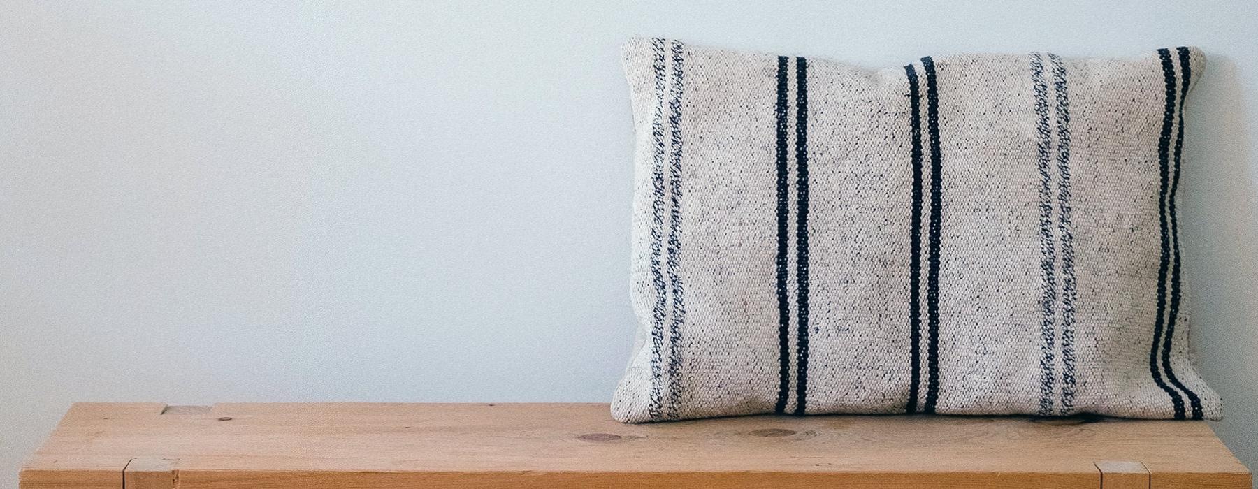 a white and black striped pillow on a bench